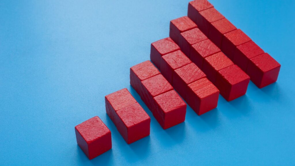 Red building blocks arranged in ascending steps on a blue background, symbolizing business growth and scalability—representing the concept that Microsoft Dynamics 365 Business Central can scale with businesses of any size.