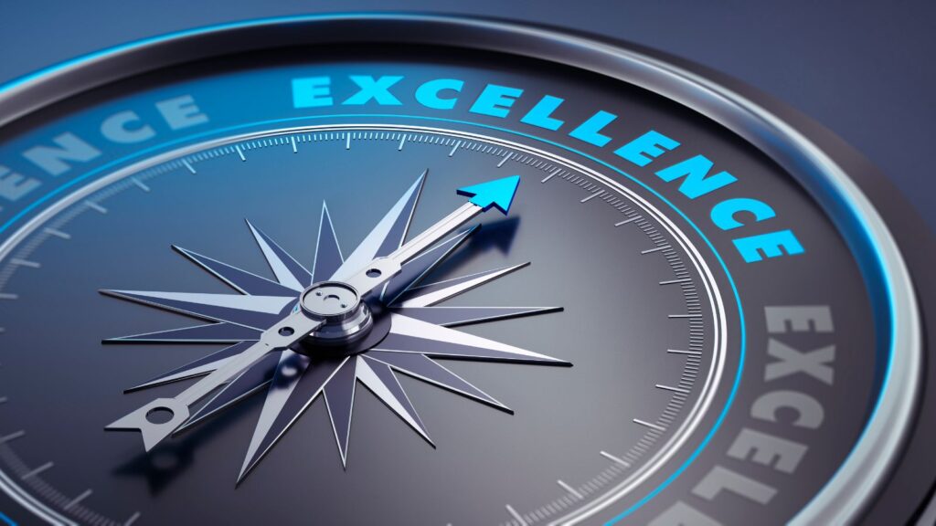 Close-up of a dark-colored compass with a glowing blue arrow pointing toward the word "EXCELLENCE," symbolizing strategic direction, high performance, and operational excellence in business.