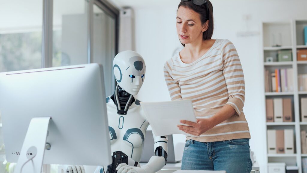 Woman collaborating with an AI robot at a computer, representing how artificial intelligence helps solve Data Migration Challenges through automation and efficiency.