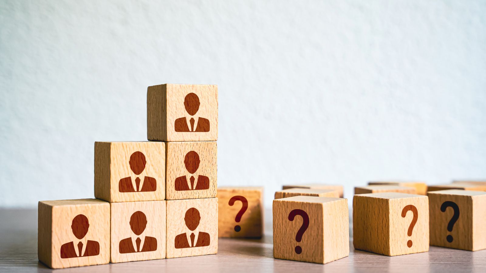Wooden blocks with businessperson icons stacked in a pyramid next to scattered blocks with question marks, symbolizing the concept that "One Size Doesn't Fit All" in ERP solutions and how Business Central adapts to companies of different sizes.