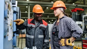 Factory team members discussing production controls on the shop floor, reflecting Lean Manufacturing through hands-on problem solving, employee engagement, and operational excellence.